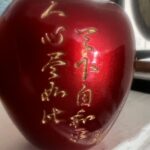 A shiny red apple with golden inscriptions, symbolizing peace and good wishes for the Lunar New Year.
